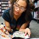 brown-skinned young woman reading comic books in bookstore